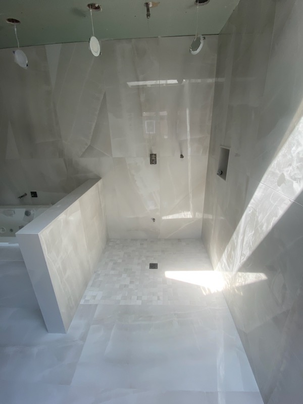 In-progress large-format marble-look shower installation with natural skylight