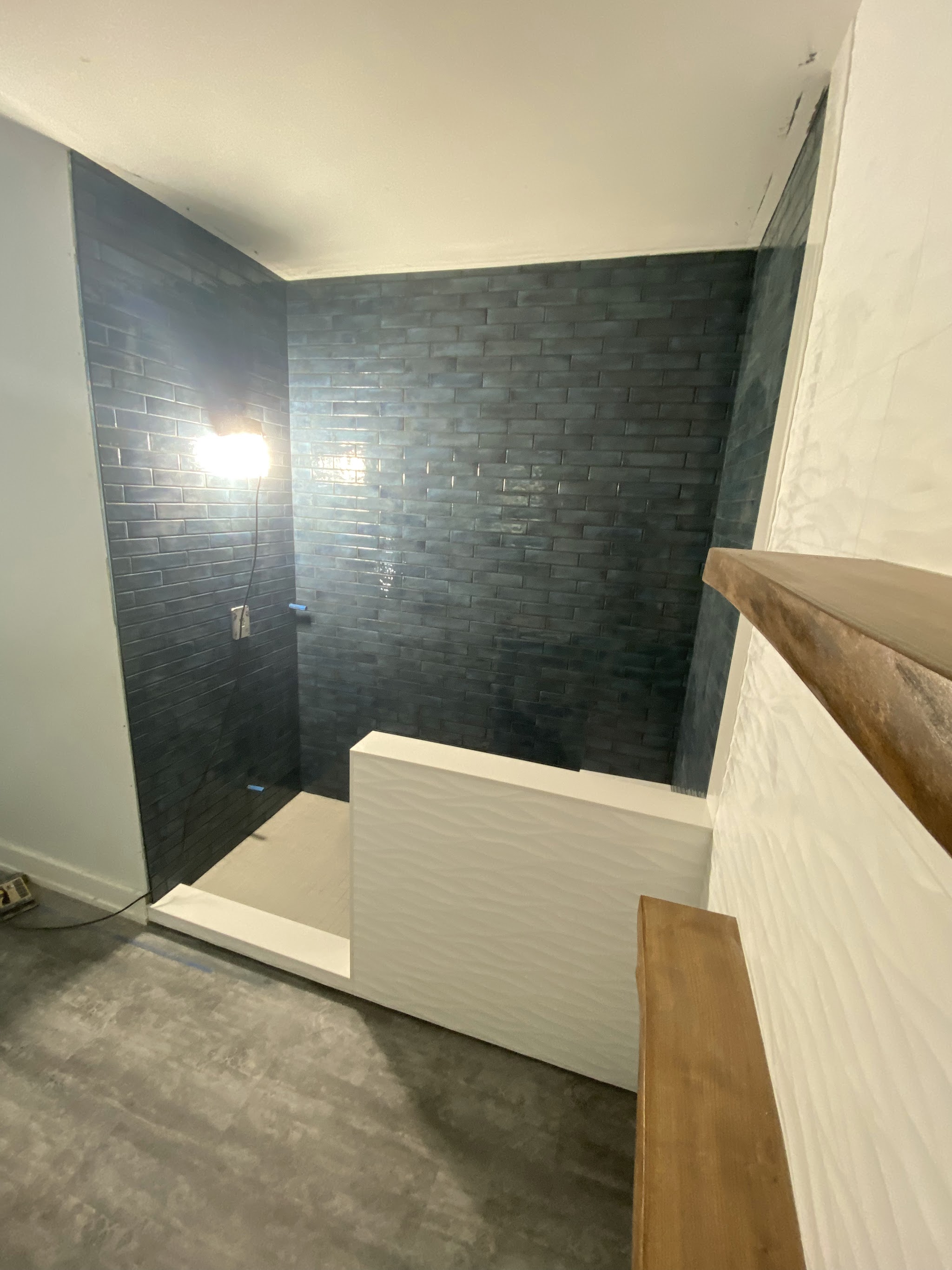Dark blue-grey brick pattern subway tile shower with wood-look accent shelf