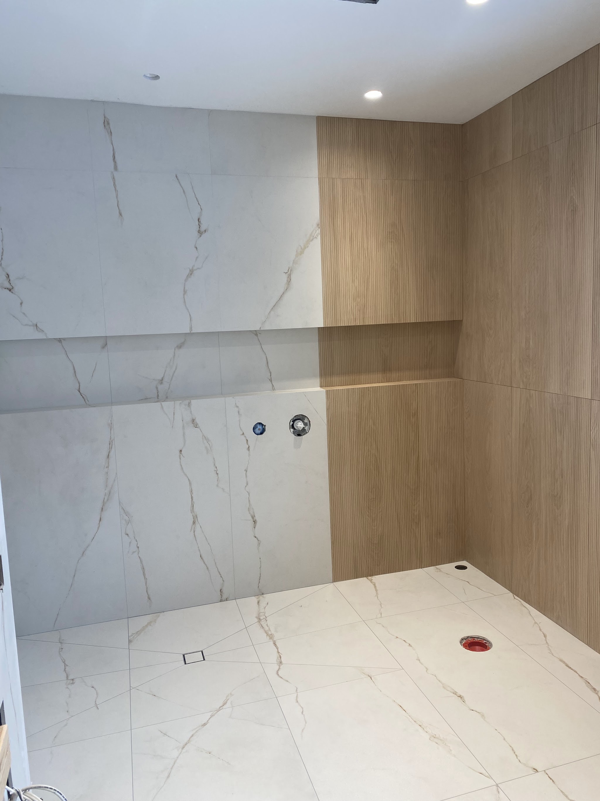 Shower combining white marble-look tile and warm wood-look plank tile