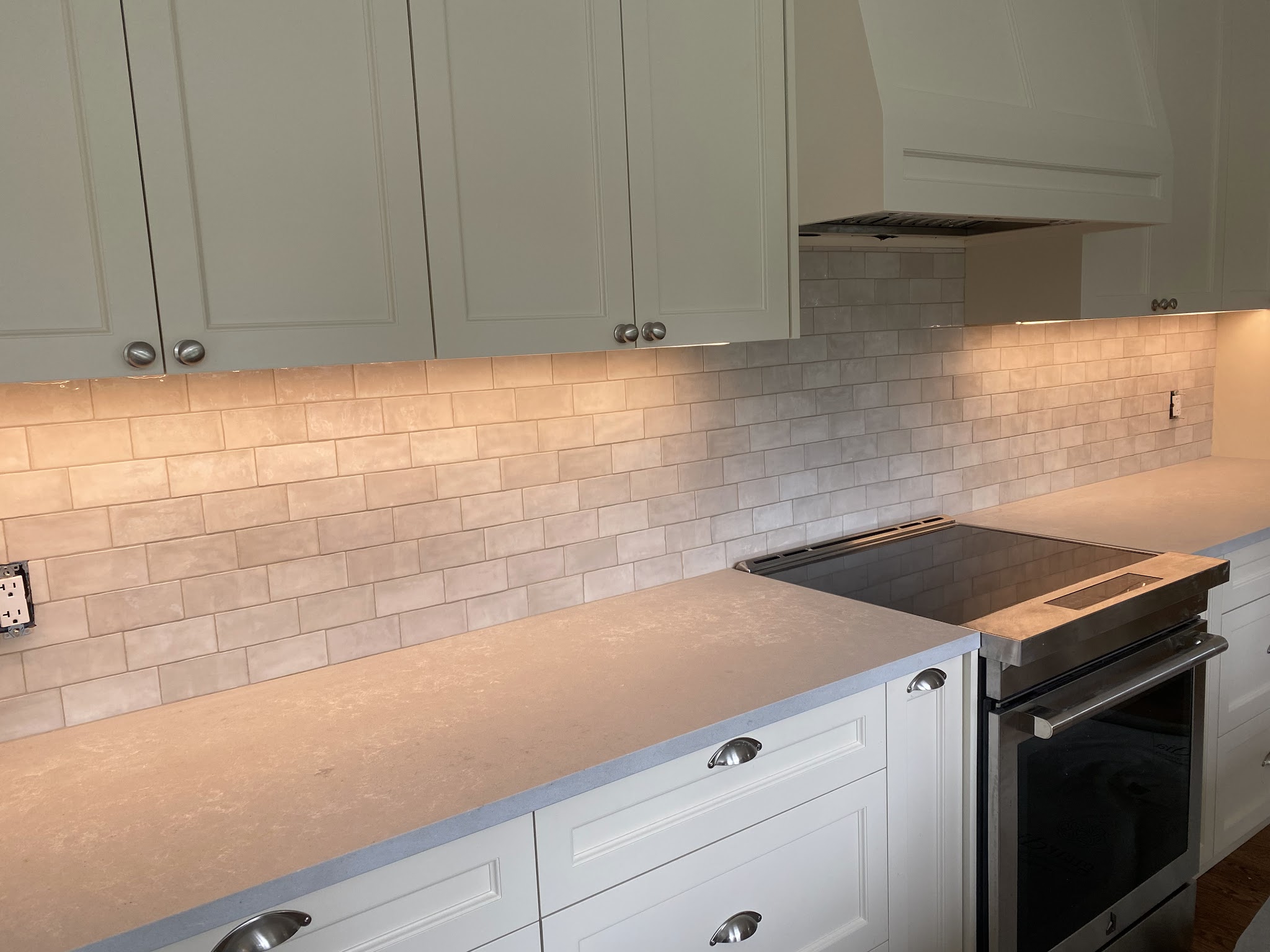 Light grey-cream subway tile kitchen backsplash under sage-green shaker cabinets